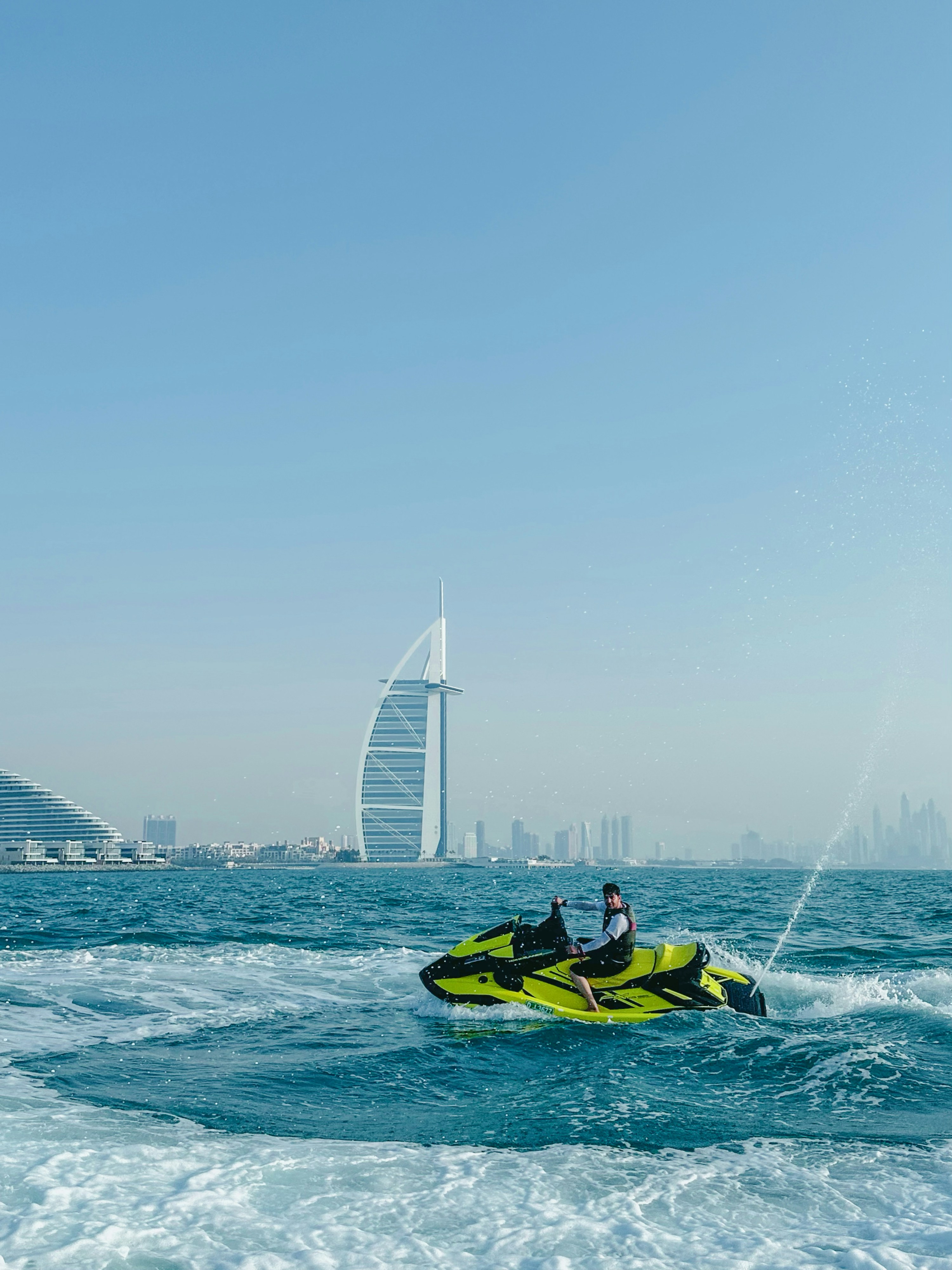 A rider on a lime-green personal watercraft, shown close up on the sea